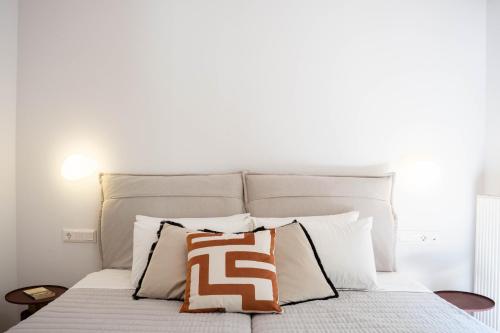 a bed with a white headboard and some pillows at Aloe & Lotus Villas in Prinés