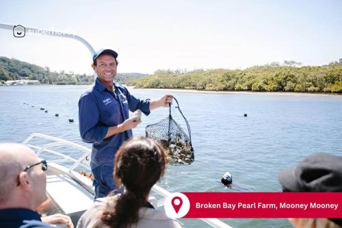 a man holding a fish in a net on a boat at Serene 5 BDRM Villa with Pool in Toukley