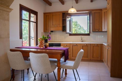 a kitchen with a wooden table with chairs and a sink at Aloe & Lotus Villas in Prinés