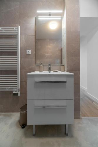 a bathroom with a white sink and a mirror at Le Grand Wilson - Appartement design - Hyper centre in Vichy
