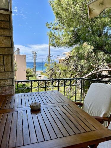 a wooden table on a balcony with a view of the ocean at Sunny Modern Beach Retreat Steps from the Shore in Saronida