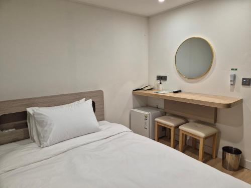 um quarto com uma cama e um toucador com um espelho em Gwang Jang Hotel em Busan