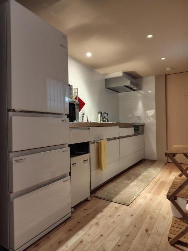 a kitchen with white appliances and a wooden floor at 香雲閣kounkaku villa in Myoko