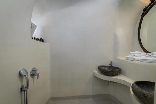 a white bathroom with a sink and a mirror at Trieris Villa & Suites in Fira