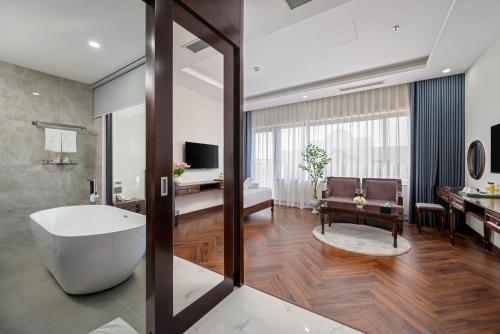 a bathroom with a tub and a living room at Florence Hotel in Da Nang