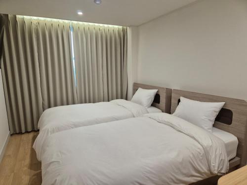 two beds in a hotel room with white sheets at Gwang Jang Hotel in Busan