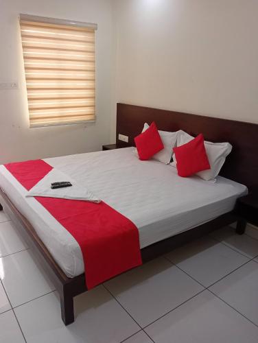 a bedroom with a large bed with red pillows at Grace Tourist Home in Ernakulam
