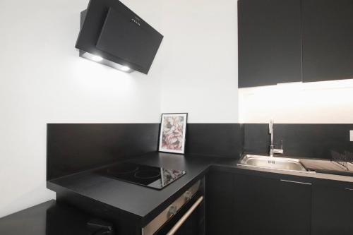 - une cuisine avec un plan de travail noir et un évier dans l'établissement La Villa Riquet Menton, à Menton