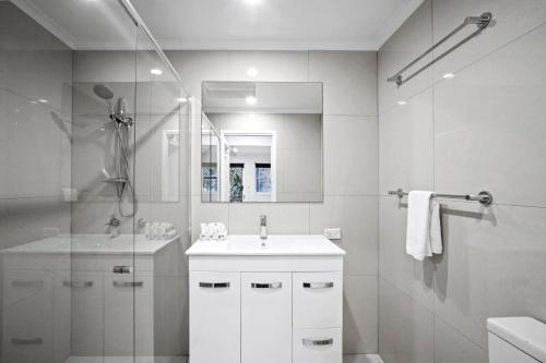 a white bathroom with a sink and a shower at Diamond Beach 35 in Gold Coast