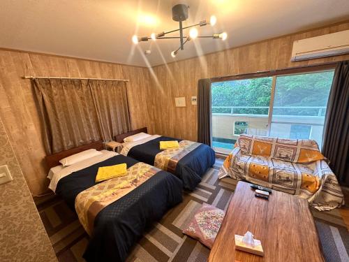 a room with two beds and a table in it at 100泊で完成する民泊 in Takamori