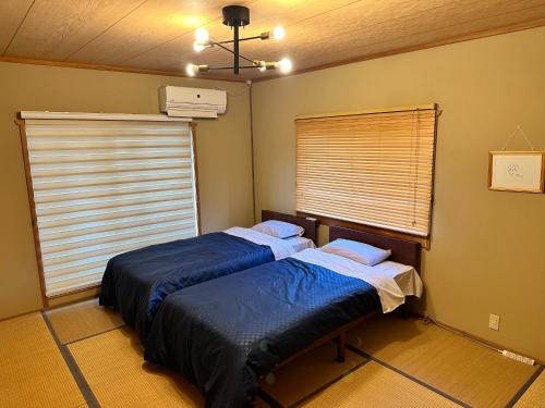 two twin beds in a room with a window at 100泊で完成する民泊 in Takamori