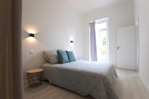 une chambre avec un lit avec des oreillers bleus et une fenêtre dans l'établissement La Villa Riquet Menton, à Menton