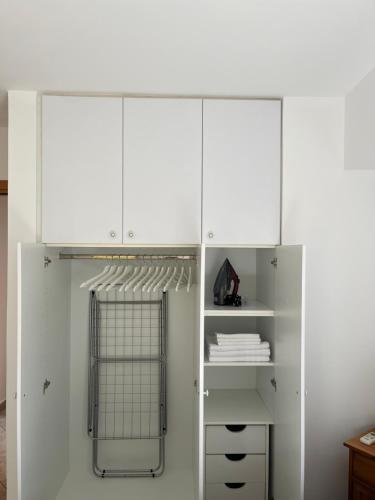 a white closet with white cabinets and a shelf at Sunny Modern Beach Retreat Steps from the Shore in Saronida