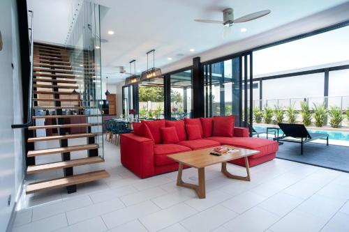 a living room with a red couch and a table at LUXURY 4BR Oxygen Pool Villa Near Nai Harn Beach - Sunset Garden 7 in Rawai Beach