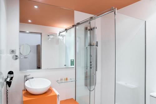 uma casa de banho com uma cabina de duche em vidro e um lavatório. em Petit Palace Plaza Málaga em Málaga