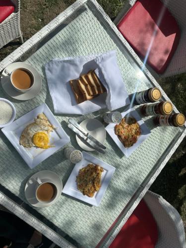a table with plates of food and cups of coffee at MONTAGNA PODS in Skardu