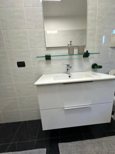 een badkamer met een witte wastafel en een spiegel bij Cozy suite with terrace in Castellanza