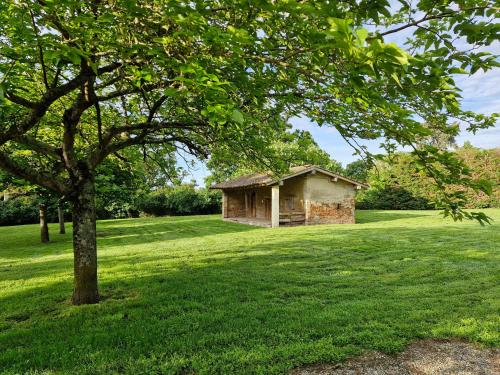 a small building in a field with a tree at Domaine Le Clos du Figuier Spa Grisolles in Verdun-sur-Garonne