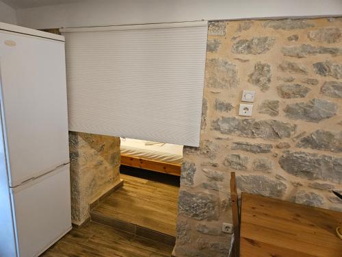 a room with a stone wall and a window with a blind at Kamares Stone House 2 in Gerolimenas