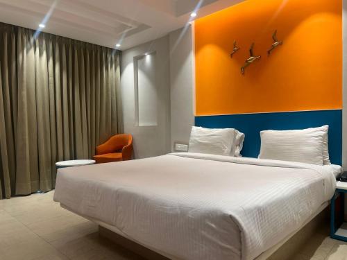 a bedroom with a large bed and an orange wall at Sparrow Hotel Managed by Siara Sariska Alwar in Alwar