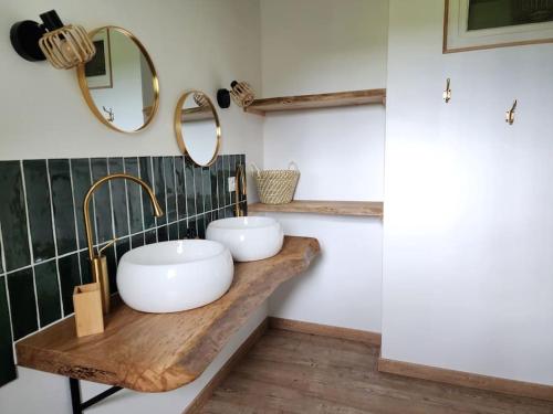 deux lavabos sur un comptoir en bois dans une salle de bain dans l'établissement Maison de Campagne, à Beaugas