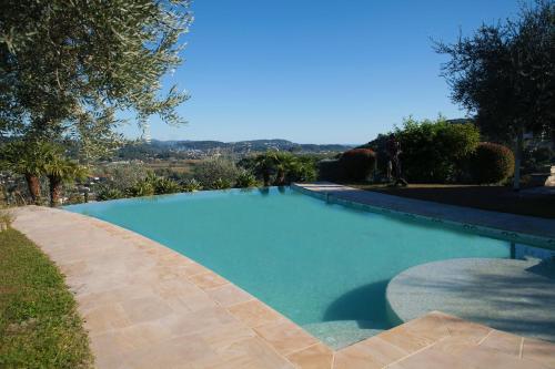 une grande piscine bleue dans une cour dans l'établissement Cannes Mas provençal piscine 8 personnes 350 m2, à Pégomas