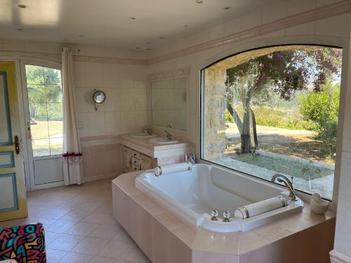 une grande salle de bains avec une grande baignoire et une fenêtre. dans l'établissement Cannes Mas provençal piscine 8 personnes 350 m2, à Pégomas