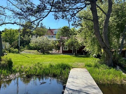 a wooden bridge over a pond in front of a house at 1800 tals Sjötorp med egen strand och brygga in Åkersberga