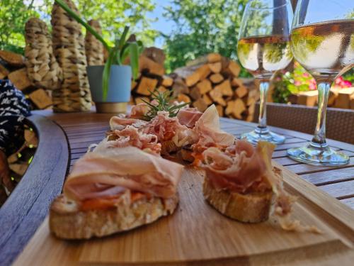 a sandwich on a wooden table with a glass of wine at Domaine Le Clos du Figuier Spa Grisolles in Verdun-sur-Garonne