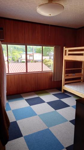 藤里町にある白神山地の麓でヤギのいるゲストハウス　あわじ商店のチェック柄の床と二段ベッドのある寝室