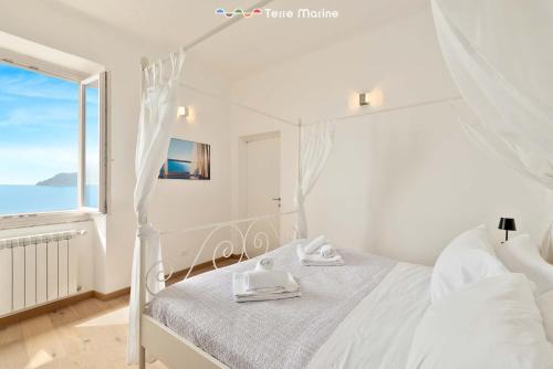 a white bedroom with a bed and a window at Oltremare, Terre Marine in Manarola