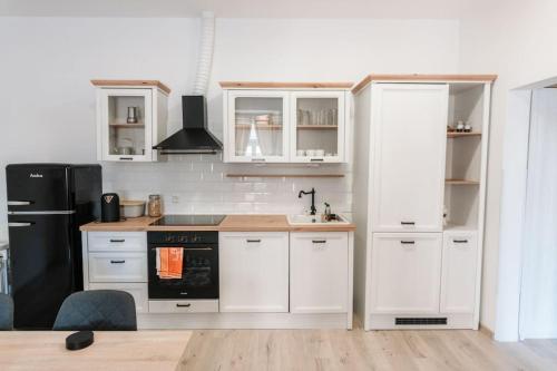 a kitchen with white cabinets and a black refrigerator at Oldie goldie in Maribor