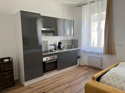 una cocina con armarios grises y una cama en una habitación en L’industriel, en Montréjeau