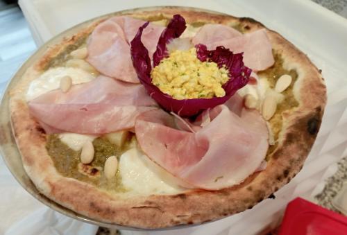 a pizza with ham and a flower on it at Hotel Paradiso in Sarnonico