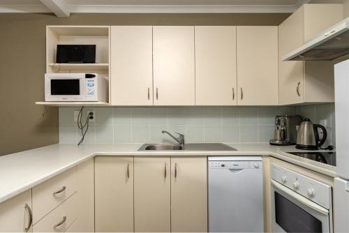 a kitchen with white cabinets and a sink at Methven Nest 2-bed Apartment in Methven