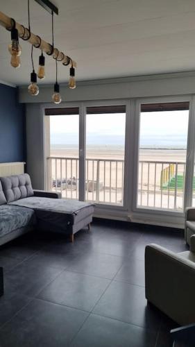 - un grand salon avec un lit et de grandes fenêtres dans l'établissement Appartement 80m2 front de mer magnifique vue panoramique, à Dunkerque