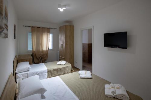 a hotel room with two beds and a flat screen tv at Elysium B&B in Mazara del Vallo