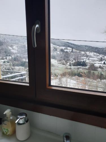 ein Badezimmerfenster mit Blick auf ein schneebedecktes Feld in der Unterkunft Maison vosgienne proche de la Bresse et Gerardmer in Basse-sur-le-Rupt