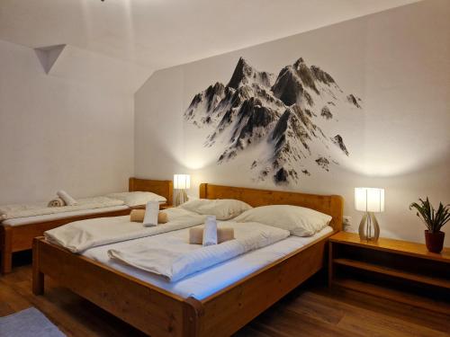 two beds in a room with a mountain mural on the wall at Penzión & apartmány Kúria na Táľoch, Tále - Chopok JUH in Tale