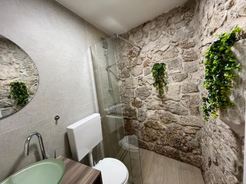 a bathroom with a toilet and a stone wall at Apartment 7 in Bol