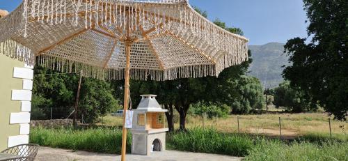 un grande ombrello di paglia con una casetta per uccelli sotto di esso di MemRo Village House a Atsoupádhes