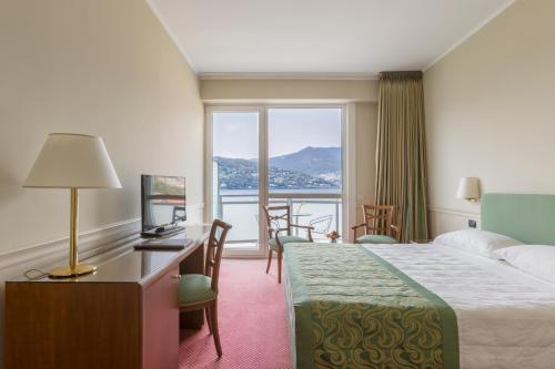 a hotel room with a bed and a desk and a window at Hotel Barchetta Excelsior in Como