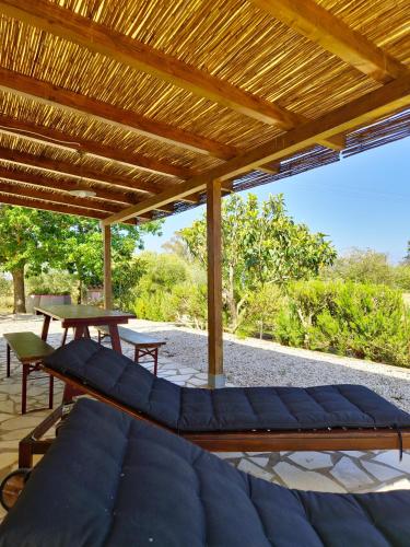 a patio with a blue couch under a wooden pergola at Casa Sicutera - Villetta indipendente situata a 4 chilometri dalla spiaggia di Su Petrosu in Orosei