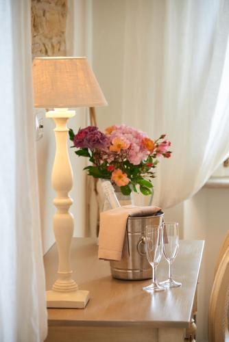 a table with a lamp and flowers and wine glasses at Pamperduto Country Resort in Porto Potenza Picena