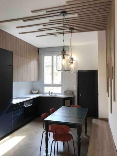 une cuisine avec une table et des chaises dans une cuisine dans l'établissement Grand appartement en maison de ville, à Valréas