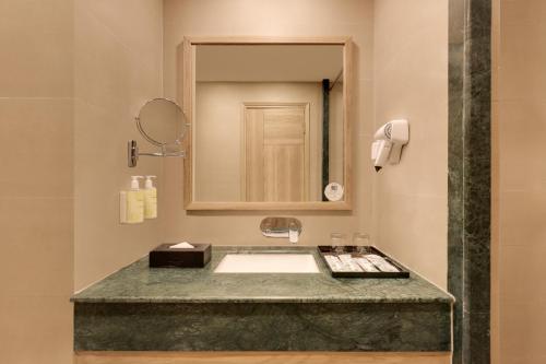 a bathroom with a sink and a mirror at Lemon Tree Hotel, Tapovan Rishikesh in Rishīkesh
