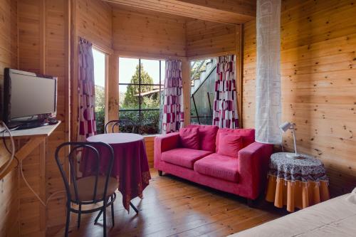 a living room with a red couch and a table at Zeus-Village οικισμός φινλανδικών chalet με πισίνες & γυμναστήριο in Mólos
