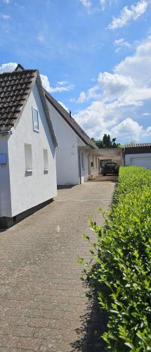 a white house with a driveway next to a garage at Ferienhaus "Dat Löppt" Bad Bramstedt in Bad Bramstedt