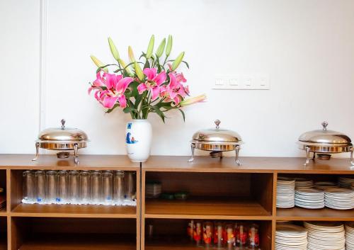 um vaso de flores cor-de-rosa em cima de uma prateleira em Song Anh Hotel Tuần Châu em Ha Long