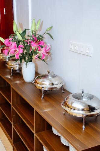 três pratos de metal sobre uma prateleira de madeira com flores em Song Anh Hotel Tuần Châu em Ha Long